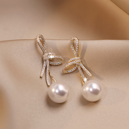 Pendientes de perlas con lazo brillante en dorado
